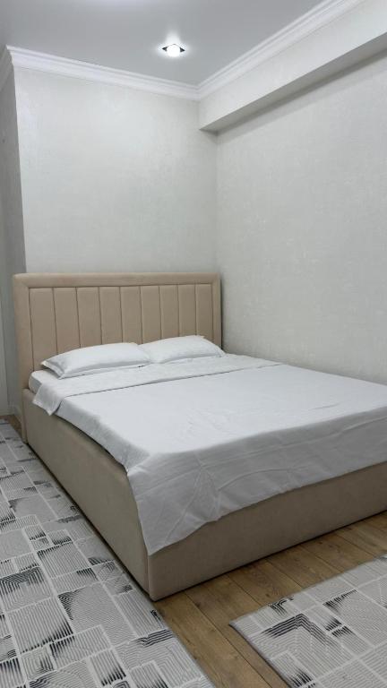 a bed in a bedroom with a white wall at АК Кеме in Osh