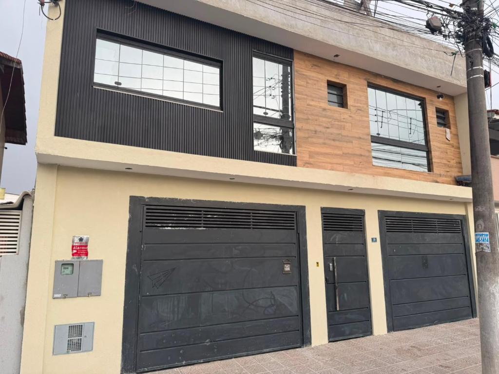 a house with four garage doors on it at Pousada SMART AIRPORT 10 min GRU in Guarulhos