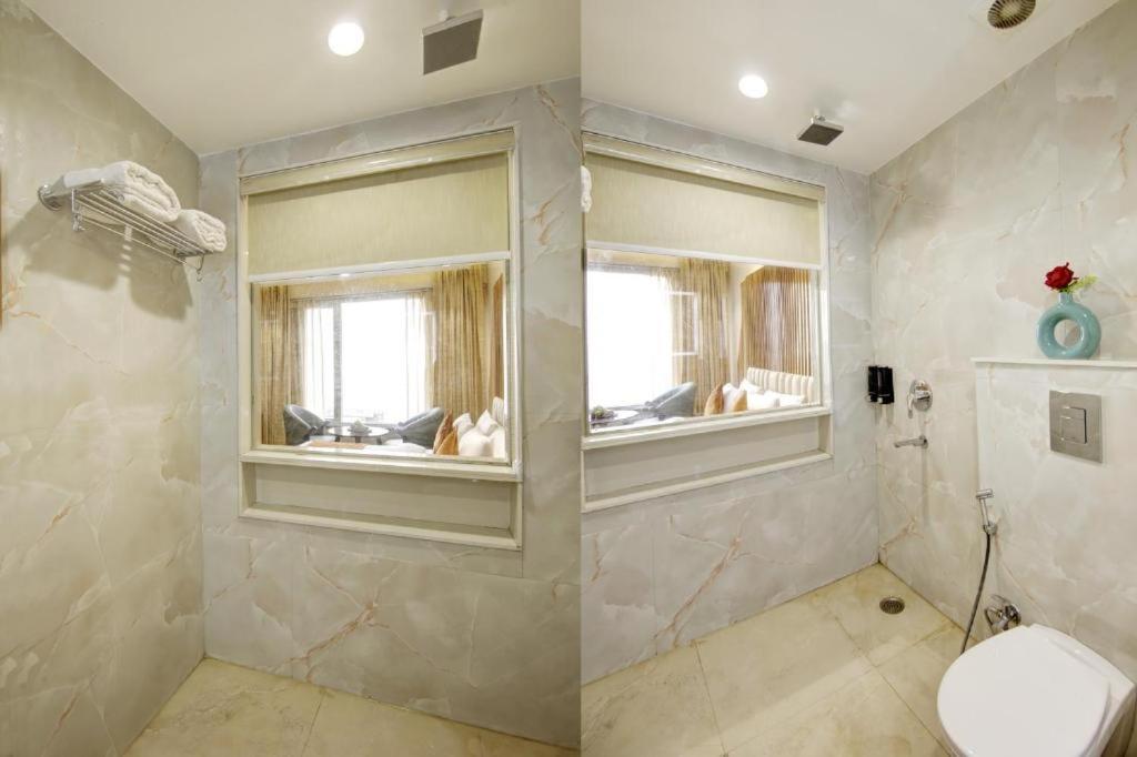 a bathroom with a shower and a toilet and a window at Hotel Shambhu Narayan G K Group Varanashi in Varanasi