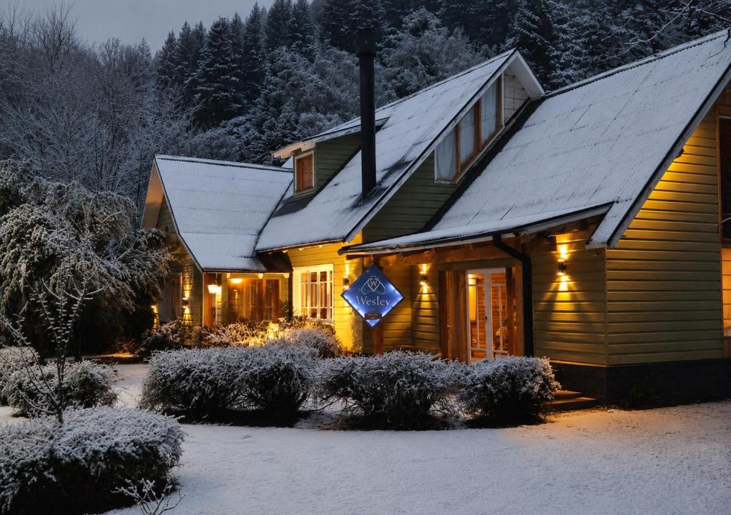 a house with snow on the roof of it at Wesley House Hosteria Boutique in San Martín de los Andes