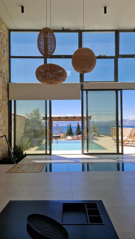a room with a swimming pool and two hanging lights at Endogeios Luxury Villas in Loutraki