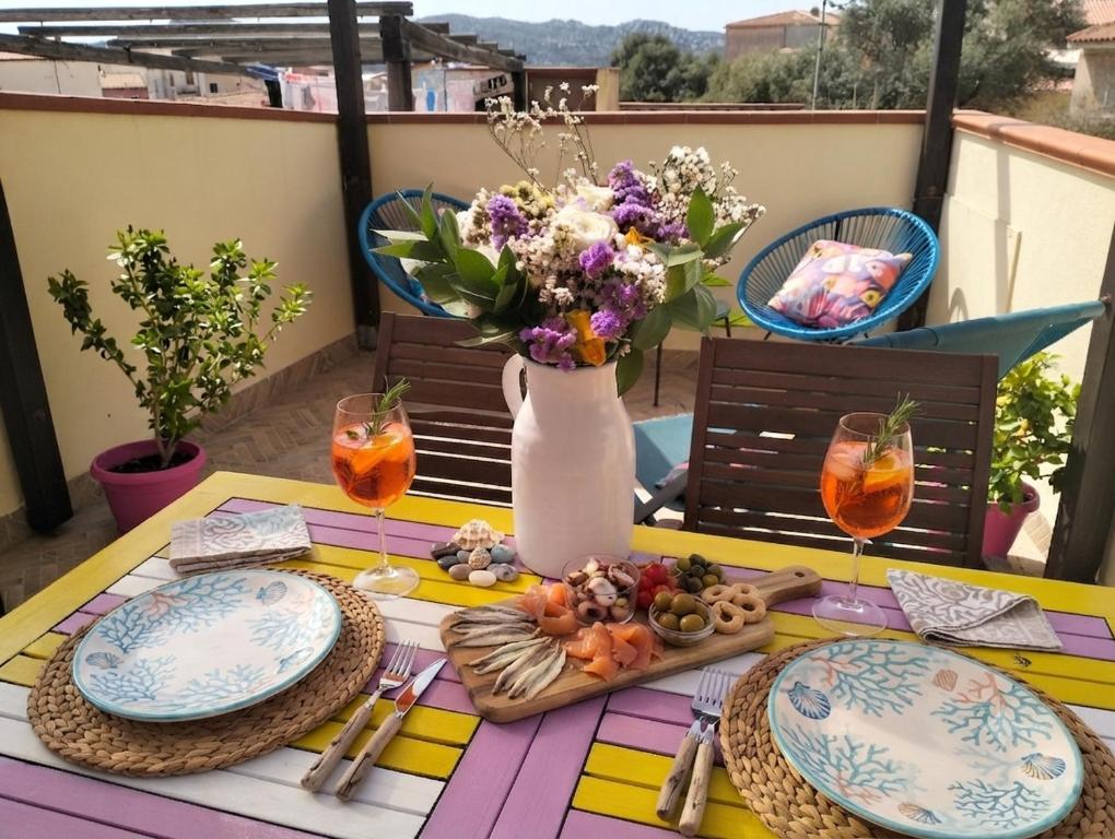 a table with plates and a vase of flowers on a balcony at Appartamento La Terrazza - Località Cala Gavetta in La Maddalena