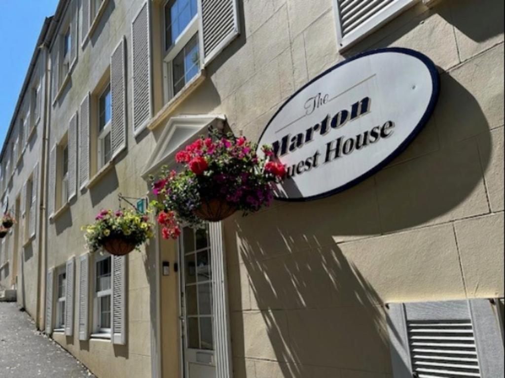 a sign on the side of a building with flowers at Marton Guest House in St. Peter Port