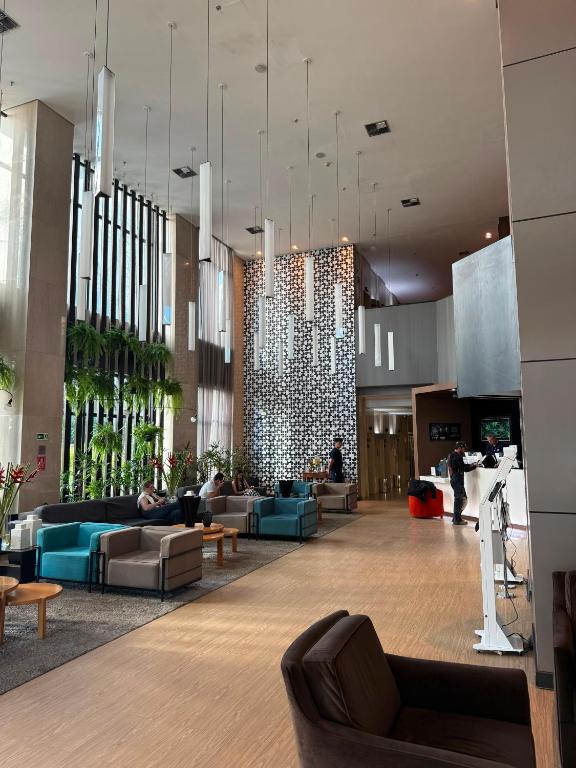 a lobby with couches and tables in a building at Lindo Flat Part Grand Mercure Varanda aconchegante in Brasília