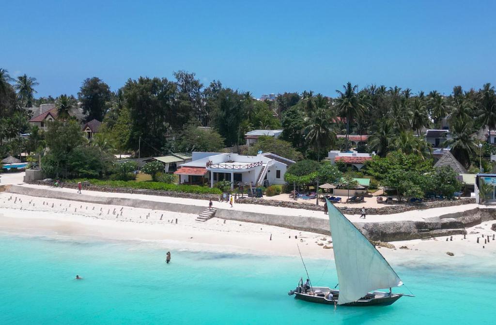 a sail boat in the water on a beach at Flame Tree Cottages in Nungwi