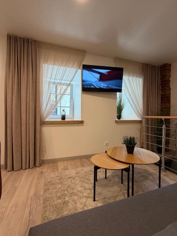 a living room with a table and a tv on the wall at Crown Apartment Secret Corner in Ukmergė