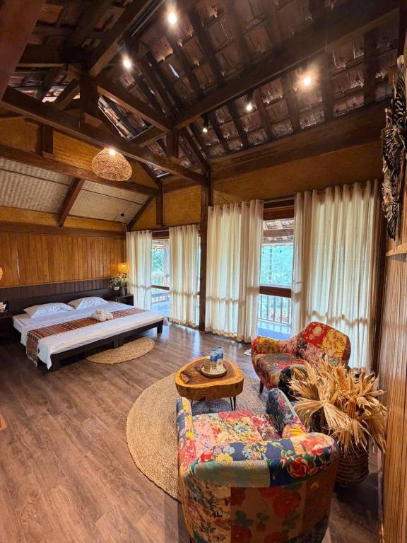 a bedroom with a bed and a couch and chairs at Bản Bọc Chăm Chứng in Làng Vach