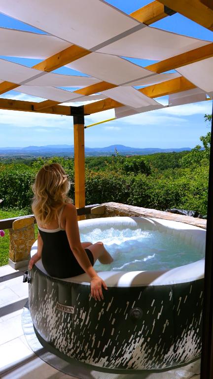 a woman sitting in a hot tub under an umbrella at Kosmaj Escape in Koraćica