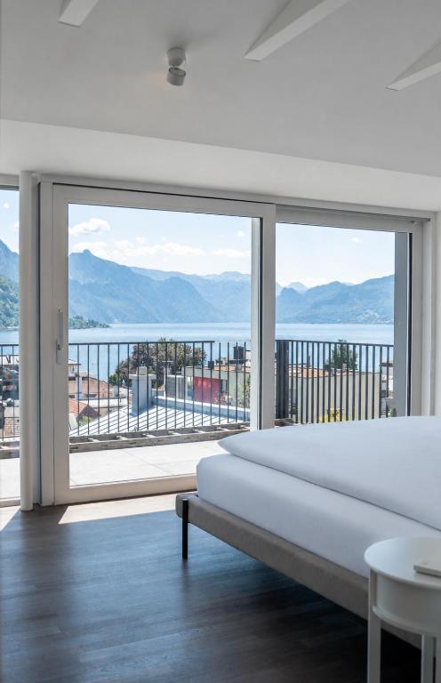 a bedroom with a large white bed and a large window at DAS ANTON - Penthouse mit Seeblick und kostenloser Garage in Gmunden