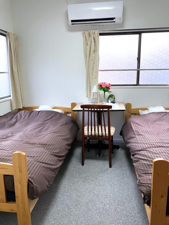 a room with two beds and a desk with a table at The Village House 1 in Hadano