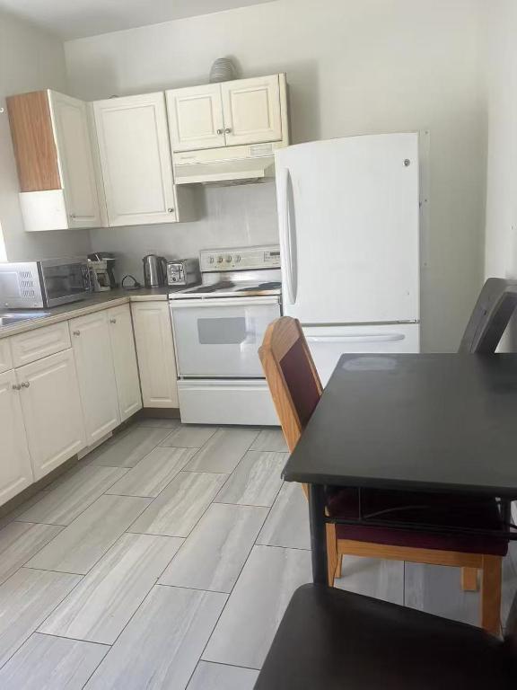 a kitchen with a table and a white refrigerator at 3 bedroom 2 bathroom garden suite in Victoria