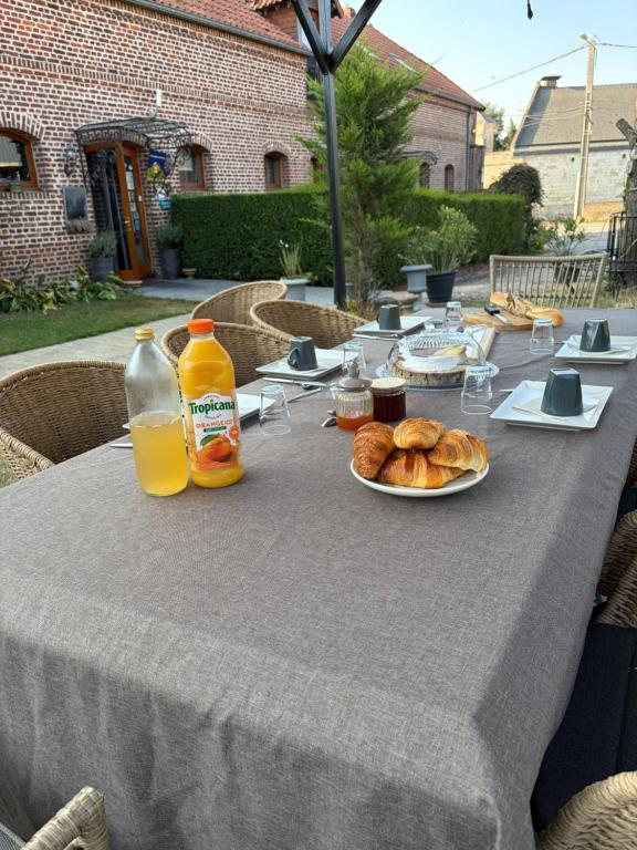 a table with a plate of bread and orange juice at Ferme de Montecouvez in Crèvecoeur-sur-lʼEscaut