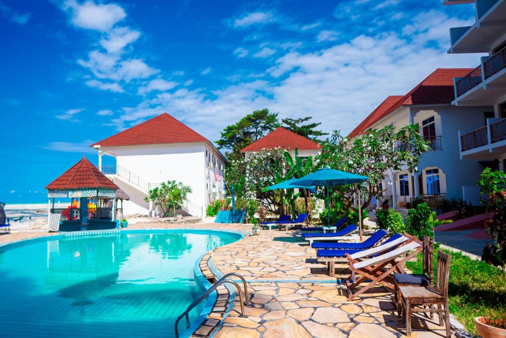 a resort swimming pool with lounge chairs and umbrellas at Visitors Inn Zanzibar in Jambiani
