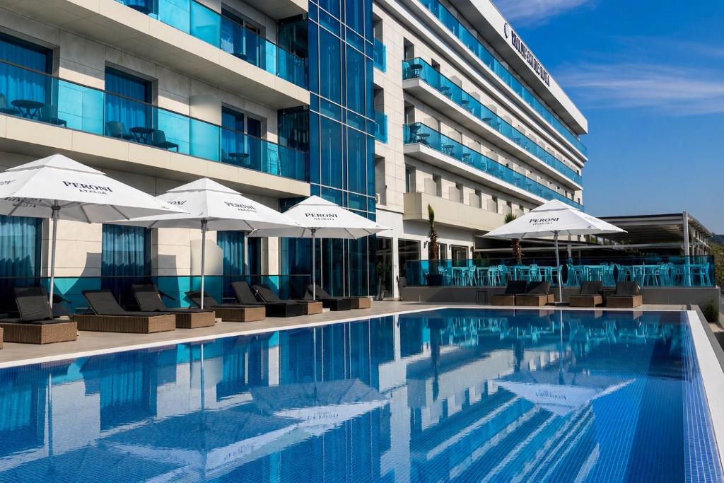 ein Schwimmbad vor einem Gebäude mit Sonnenschirmen in der Unterkunft Hotel Union in Eforie Nord