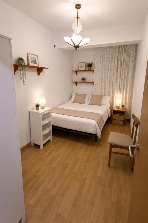 a bedroom with a white bed and a chair at Apt Puerto Burriana in Burriana