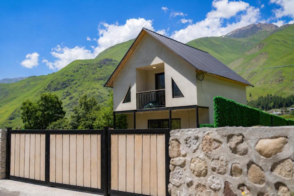 a house with a fence and mountains in the background at Cottage Shina in Kazbegi