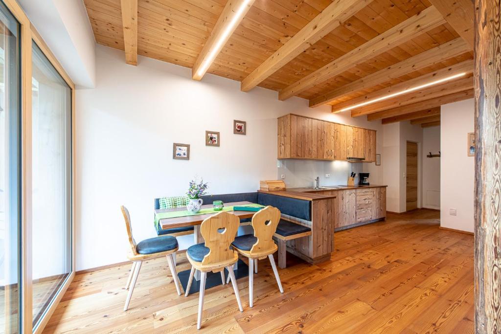 a kitchen with wooden floors and a table and chairs at Kreuzplonhof Apt Dorfblick in Luson