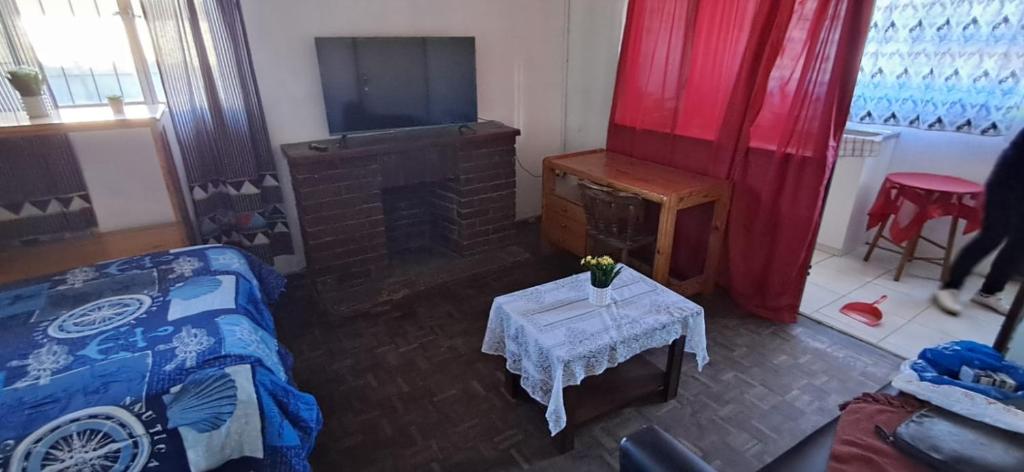 a living room with a bed and a fireplace and a table at Kuils River Apartment, near Cape Town Airport in Sarepta