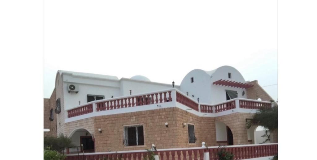 a large house with a brick and white at La villa jasmin in Al Maqārisah