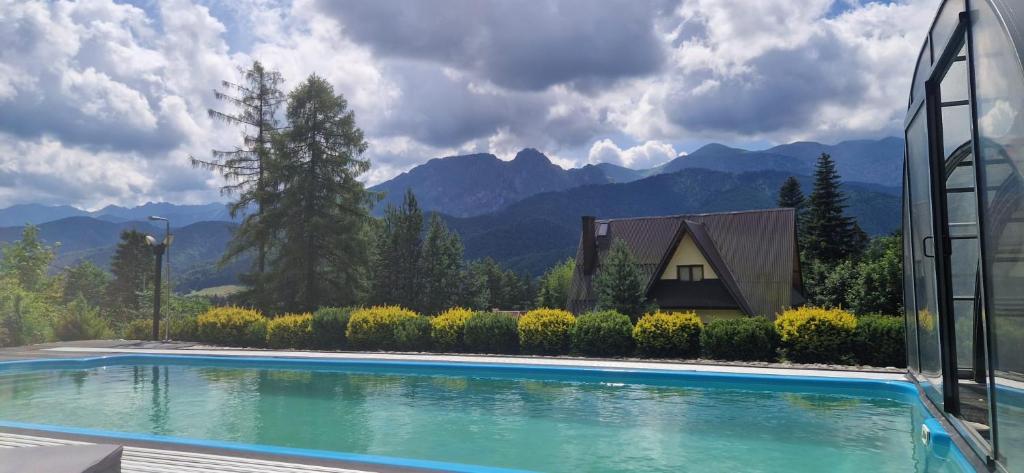 a swimming pool in front of a house with mountains at Secret Residence with Sauna & Private Pool in Kościelisko