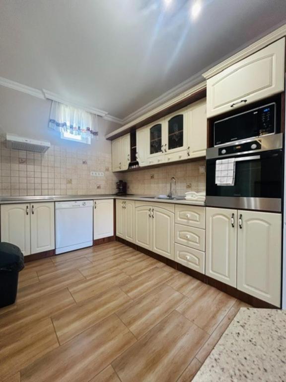 a large kitchen with white cabinets and a wooden floor at Csuszka vendégház in Tiszafüred