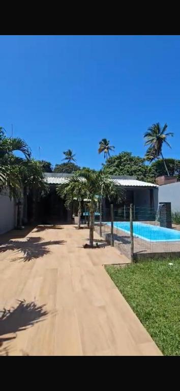 a walkway next to a swimming pool with palm trees at Casa 108 in Guaibim