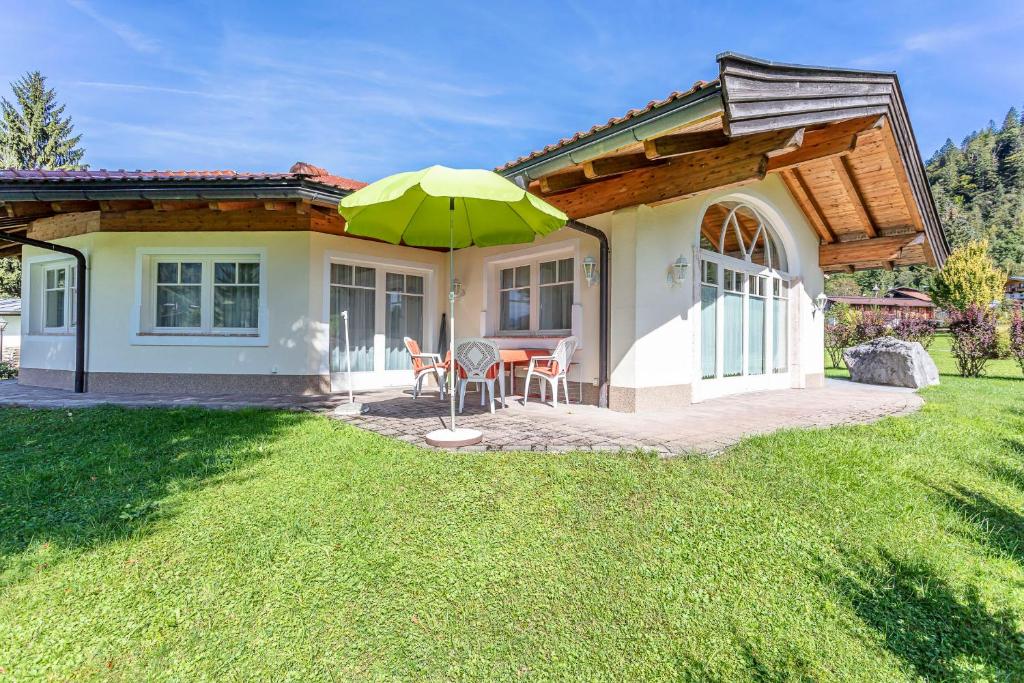 a small house with a green umbrella in the yard at Berghof-Chalet in Erpfendorf