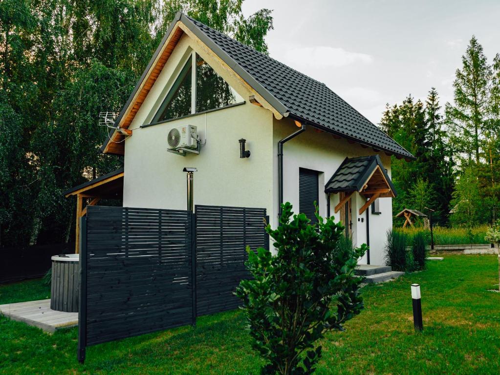 a small house with a black fence in a yard at Świtówka - Domek z balią ogrodową in Żnin