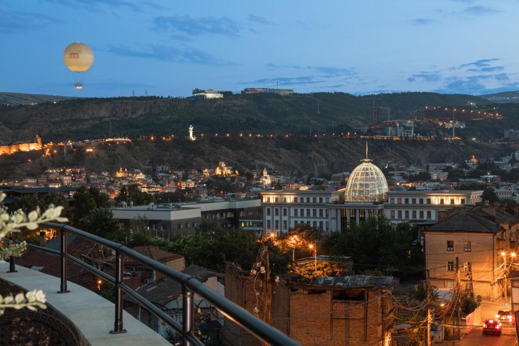 a hot air balloon flying over a city at night at Panorama Boutique Hotel in Tbilisi City