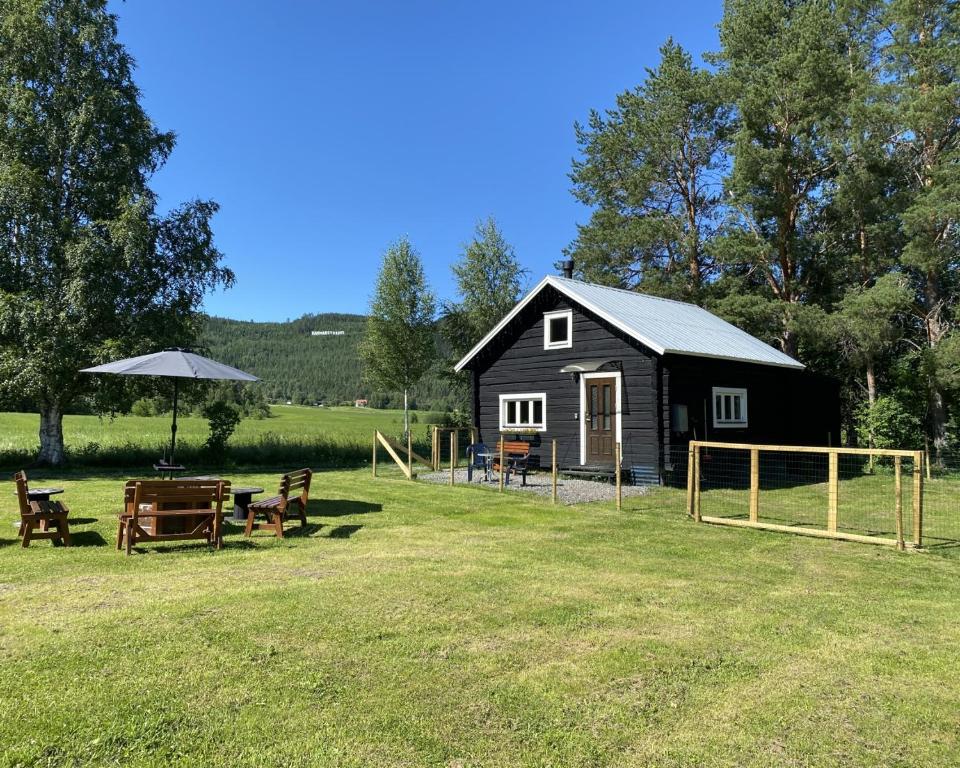 a black shed with a picnic table and benches in a field at Villa Ragunda in Hammarstrand