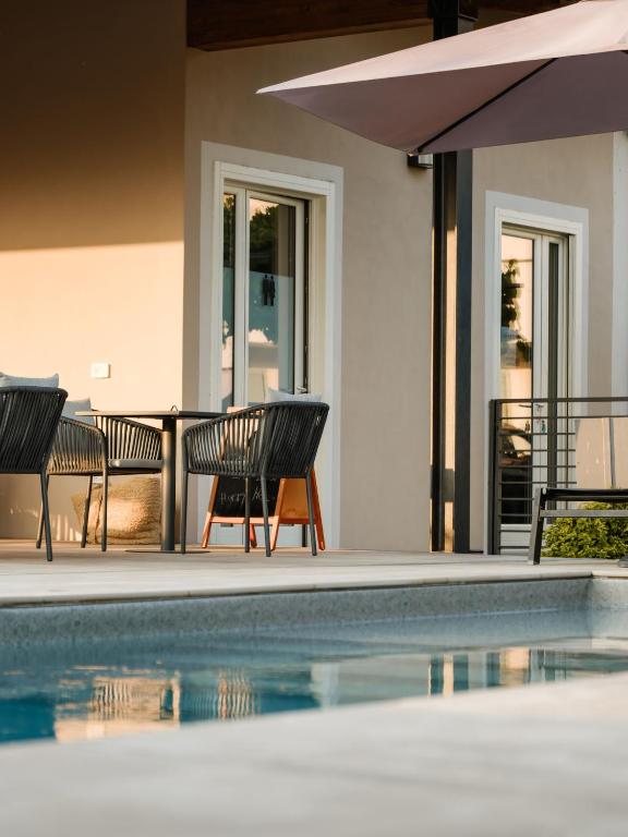 a pool with two chairs and a table and an umbrella at Villa Curte Nicia in Nizza Monferrato