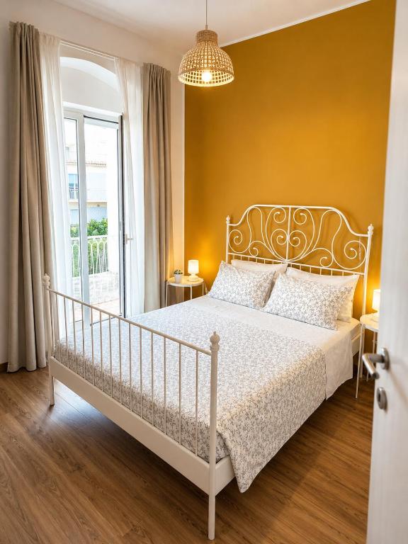 a bedroom with a white bed and a yellow wall at Matinee Rooms in Mattinata