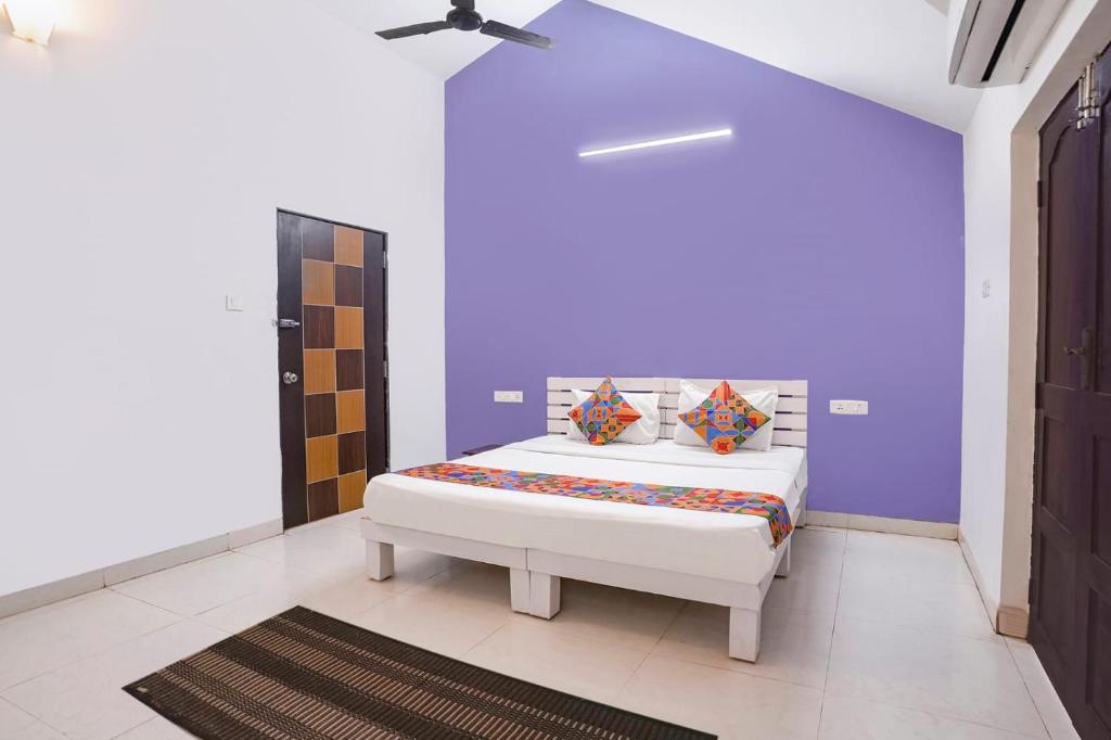 a bedroom with a bed and a purple wall at Triple Beach Guest House in Benaulim