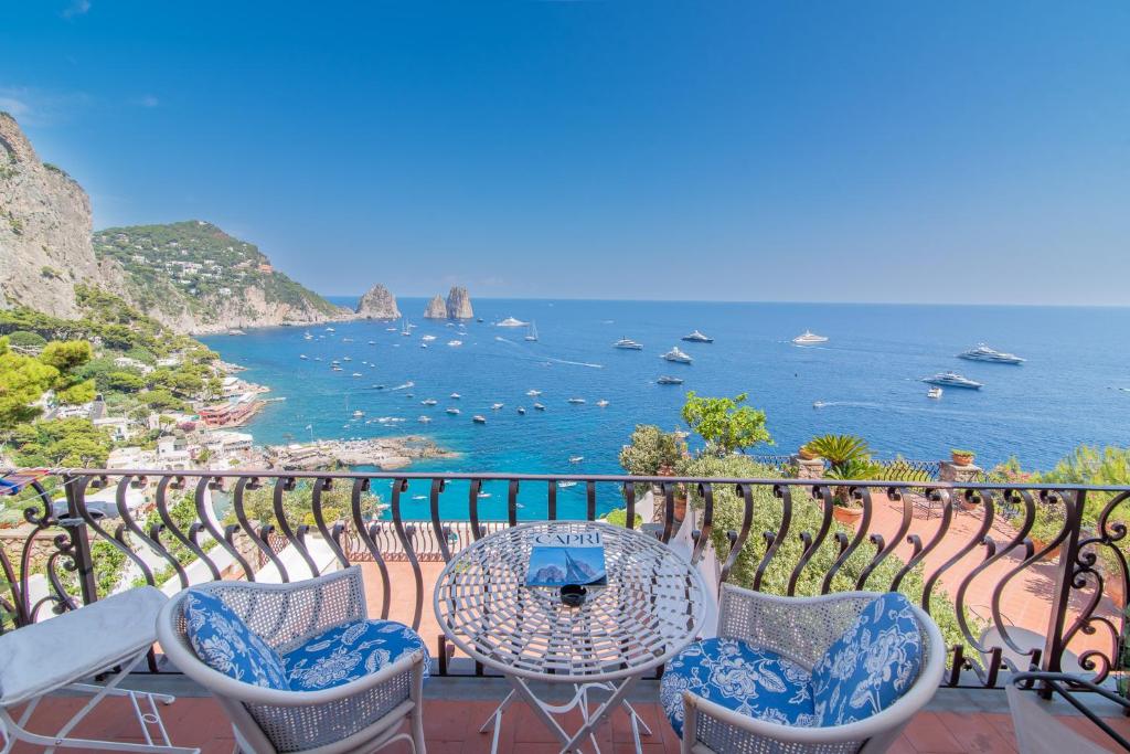 a balcony with a table and chairs and the ocean at Casa vista Faraglioni Capri 2 in Capri