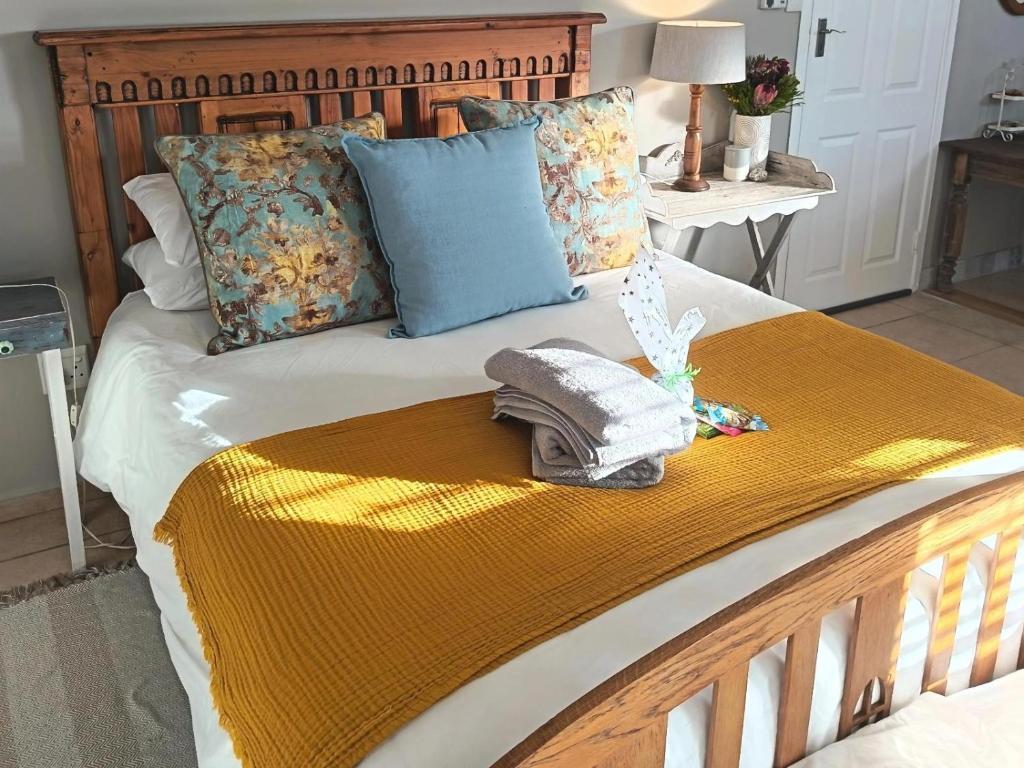 a bed with a yellow blanket and pillows on it at Nouvelle Vie Self-catering Accommodation in Reebok