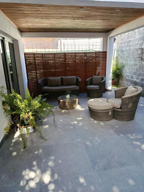 a patio with couches and chairs and a table at LaKaz Pascale T2 climatisé pour 4 adultes 1 enfant in Ravine des Cabris