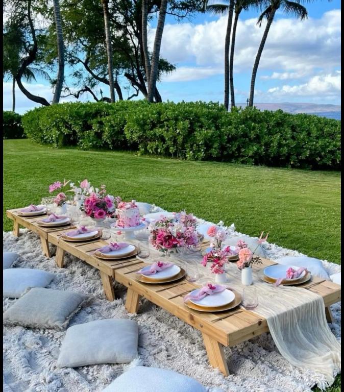 a wooden table with plates and flowers on it at Golden Hour in Cockburn Harbour
