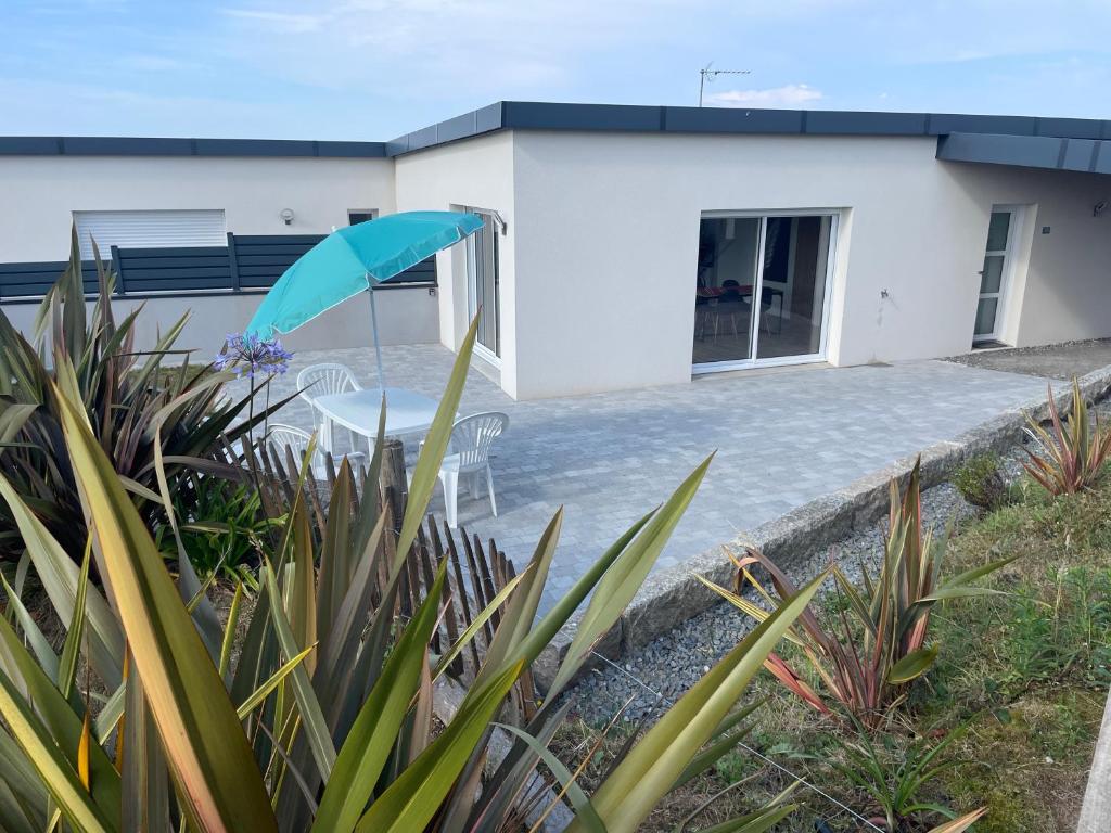 a white house with a table and an umbrella at Chez Tristan in Plouguerneau