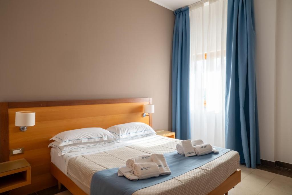 a bedroom with a bed with two towels on it at Hotel Scoglio Degli Achei in Torre Santa Sabina