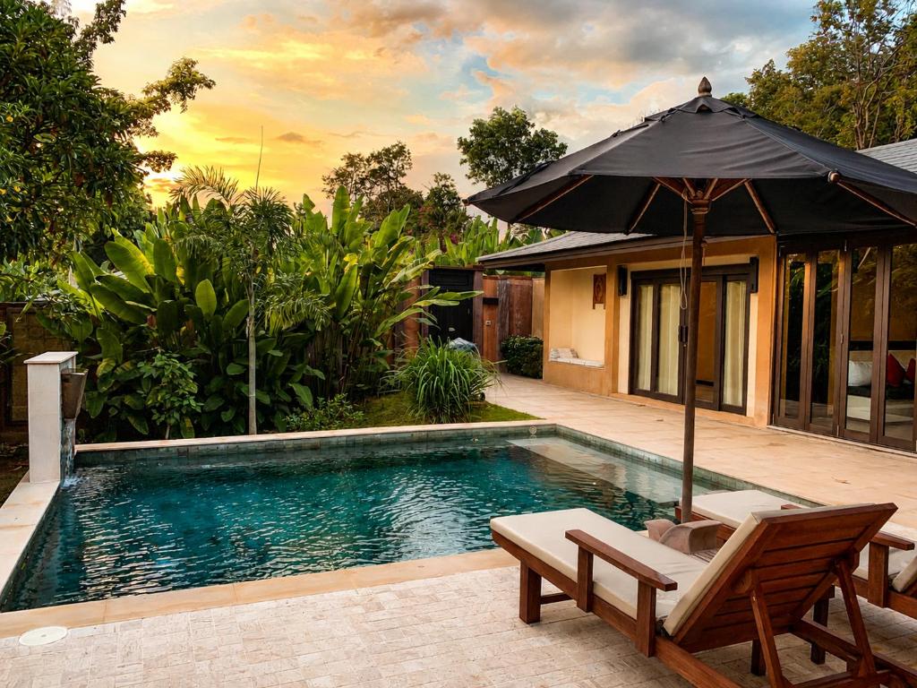 a swimming pool with an umbrella and a chair at Alanta Private Pool Villa in Ko Lanta