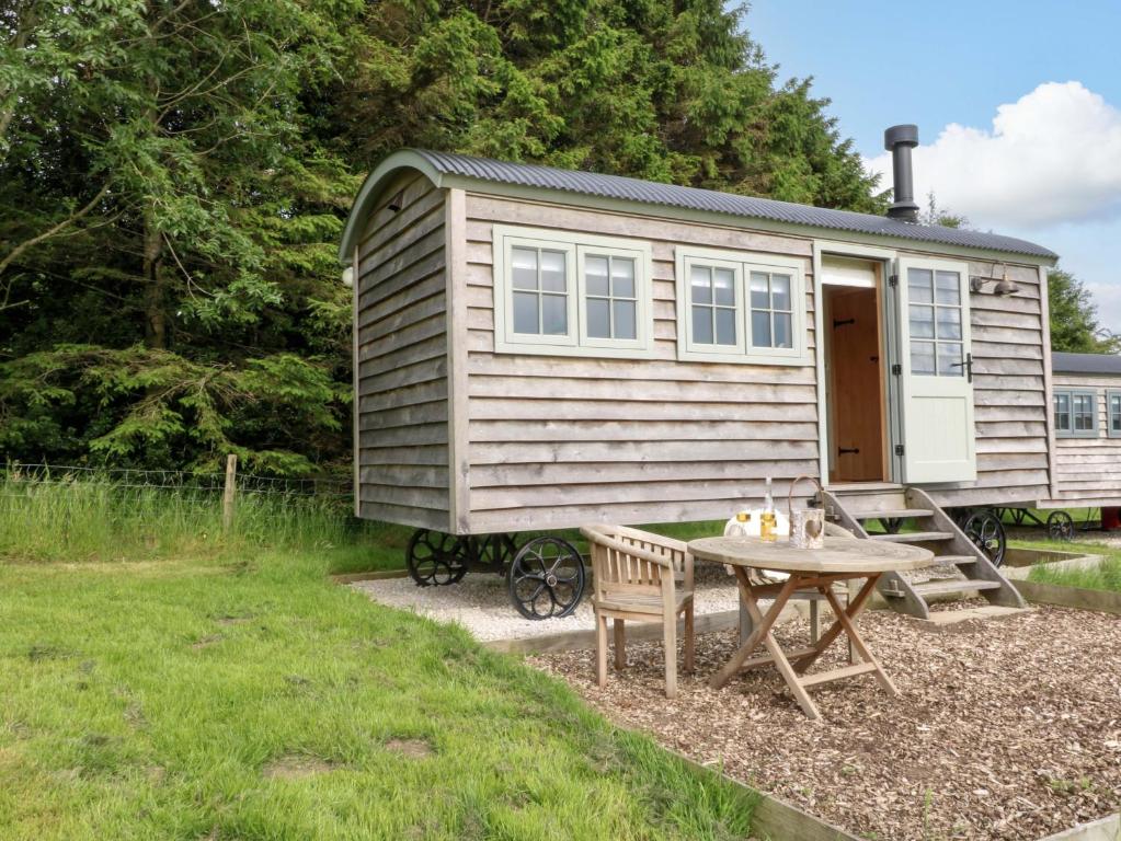 a tiny house on a trailer with a table at Meadow Shepherds Hut in Ashbourne