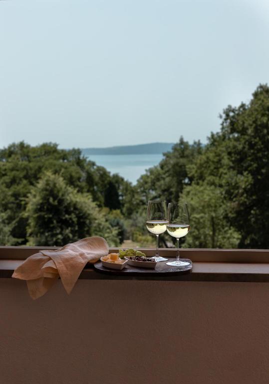 a table with two glasses of white wine on a balcony at The Lake Escape - Trevignano in Trevignano Romano