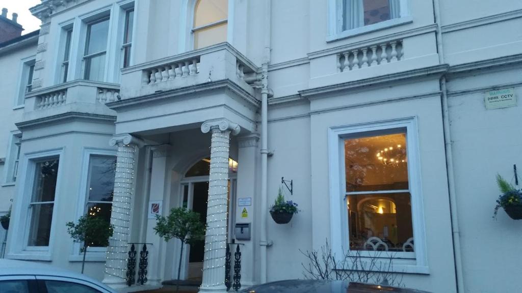 a white building with a balcony on a street at Episode Hotel in Leamington Spa