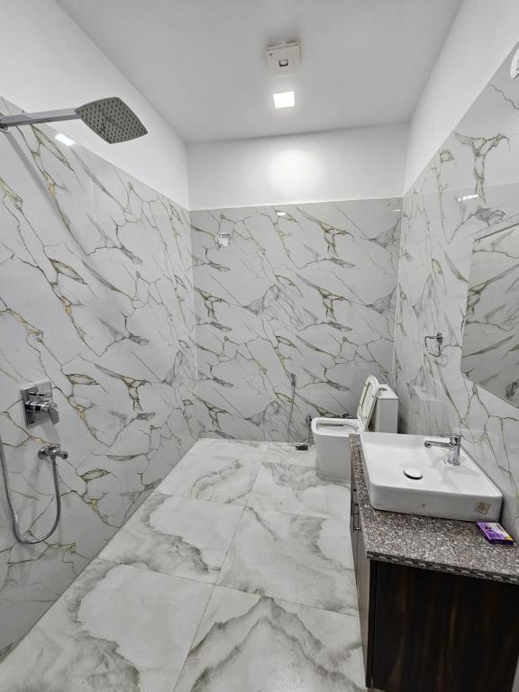 a marble bathroom with a sink and a toilet at Hotel B Anand in Aonla
