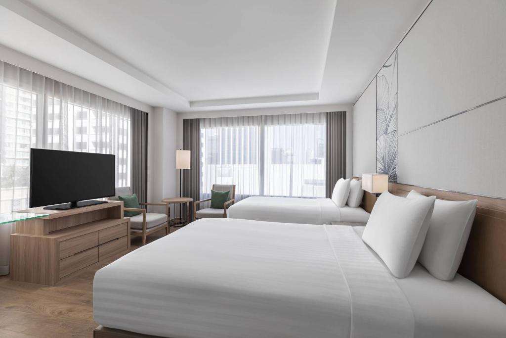 A two-bed room arranged around a television, seating area and broad windows.