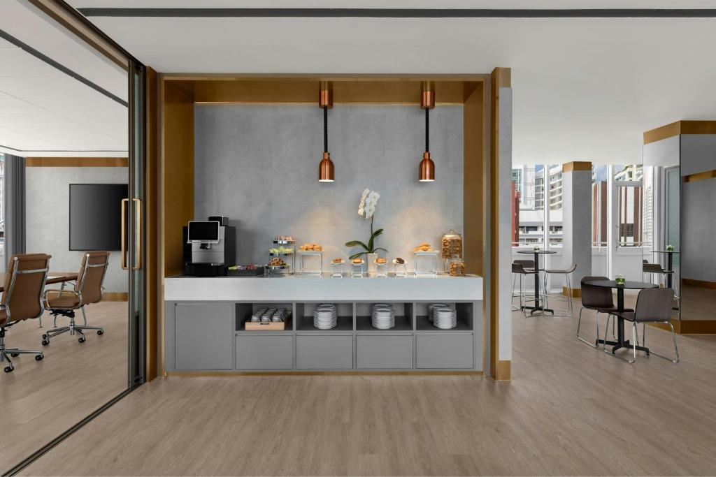 An open lounge with a buffet-style refreshment counter, adjoining meeting room and city-facing windows.