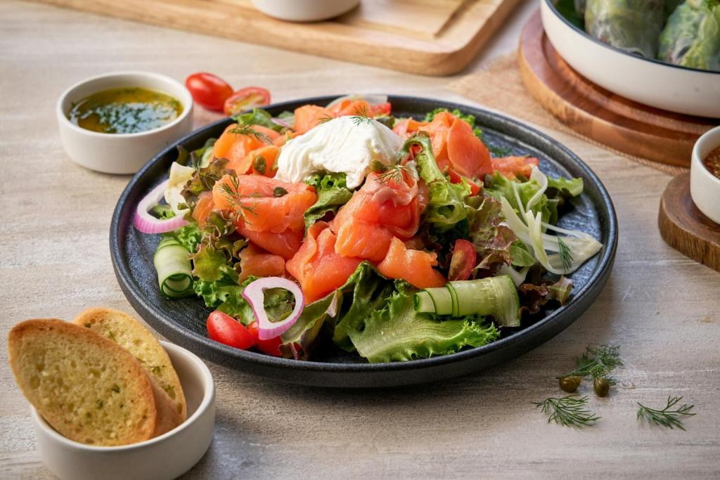 A composed salad plate with smoked salmon, greens, cucumber, egg and toasted bread.