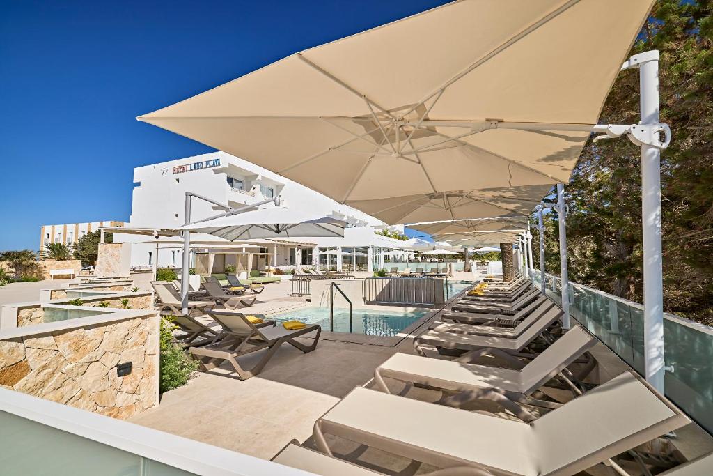 an outdoor patio with lounge chairs and an umbrella at Lago Playa in Es Pujols