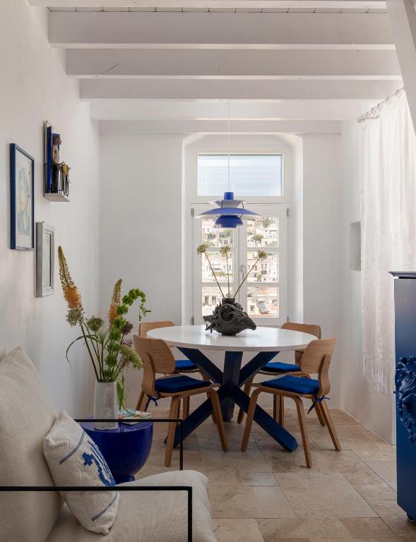 a dining room with a white table and chairs at Allium Art House Symi in Symi