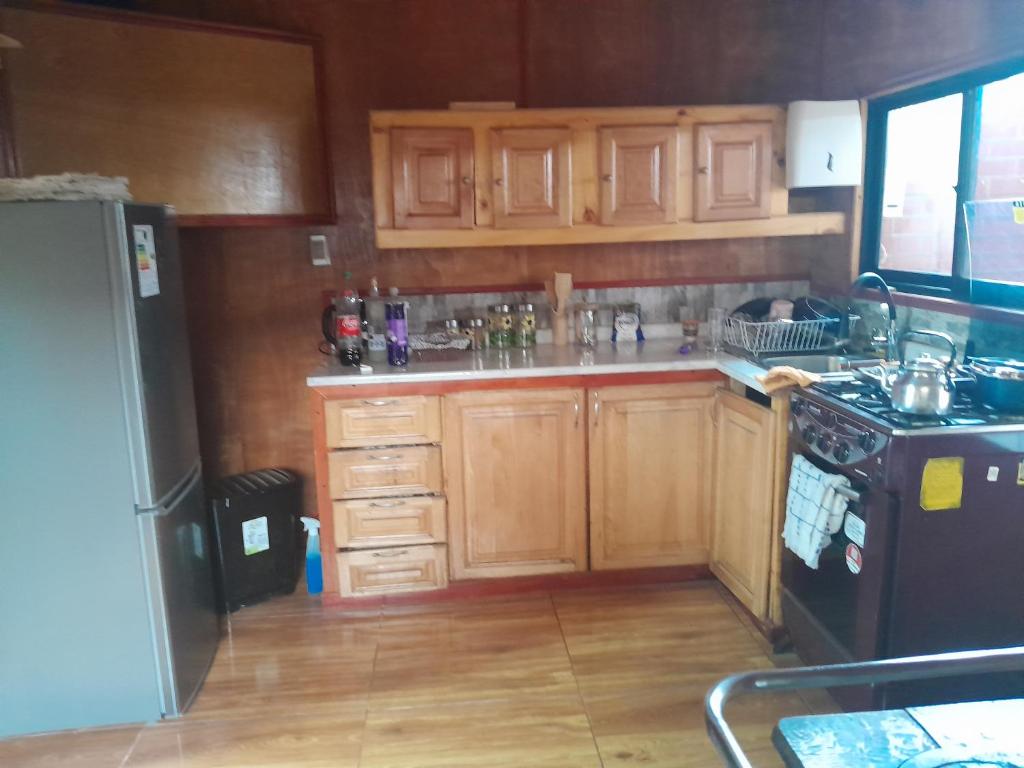a kitchen with wooden cabinets and a black refrigerator at Isidora in Puerto Aisén